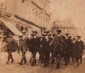 Pte Bertie Hibbett is marching behind his brother Sydney (in mufti, front row far left). Bridge Street, Walsall. Sept. 1914.